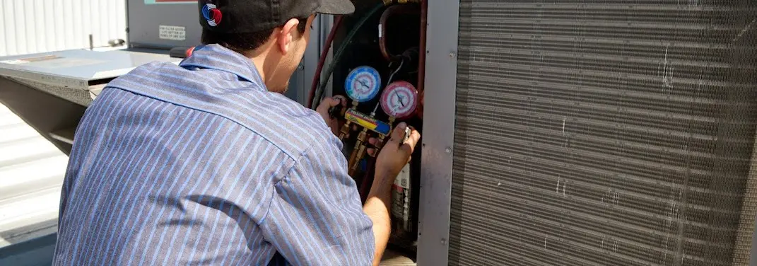 HVAC technician servicing a condenser unit in Camp Pendleton Mainside